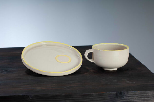 cappuccino cup and saucer with yellow rim side by side